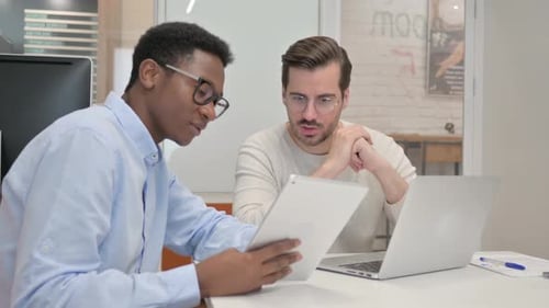 Men Discussing Tablet at Office Desk