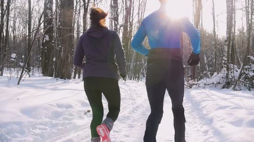 Winter Forest Young Man and Woman Running on the Trail