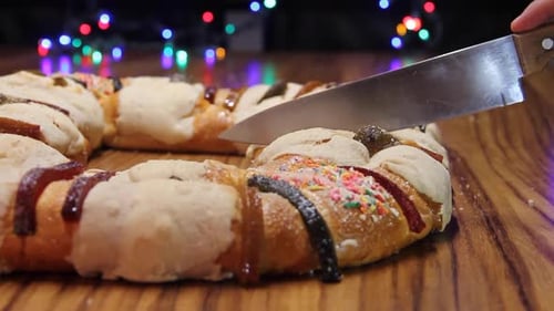 rosca de reyes in foreground on wooden table with out of focus background of colored light