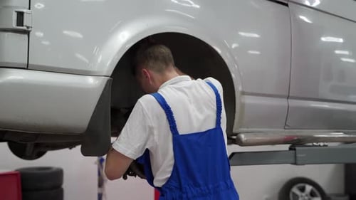 Auto Mechanic in Uniform Fixes Vehicle Suspension Performs Maintenance at Car Service Garage Male