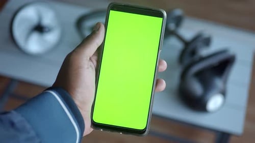 Man Hand Holding Green Screen Smart Phone in Gym