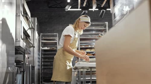 Beautiful Caucasian Woman in Cooking Uniform Cutting Dough and Shaping Cookies in Bakery Baking