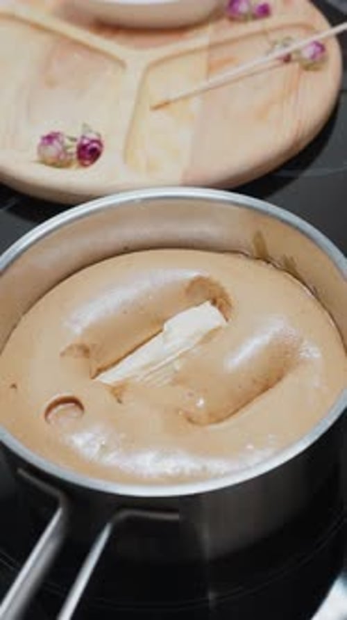 Woman Dropping Butter Into Steaming Pap on Electric Stove