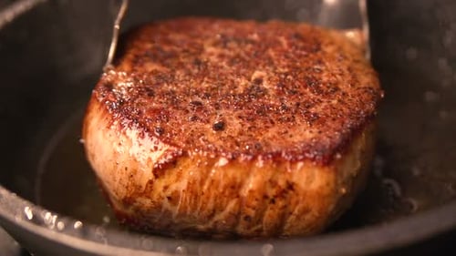Juicy red beef steak sizzles on a grill in rapid and slow motion cooking
