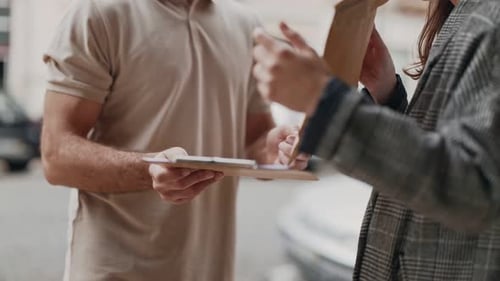 Woman Signing for Package From Delivery Man