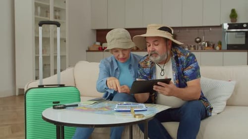 Cheerful Mature Tourist Couple Planning Journey on Cruise Ship Using Tablet Pc