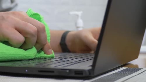 Office Male Worker Using Spray Disinfection Gel Sanitizing and Wiping Keyboard of Laptop