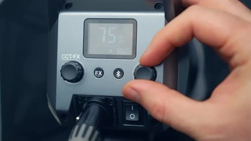 Finger eines Kameramanns, der die LED-Videoleuchte einschaltet und ihre Helligkeit aus der Nähe einstellt