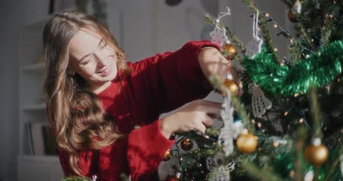 Woman Decorating Christmas Tree with Ornaments at Home