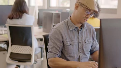 Produktiver Mann, der Computer benutzt und dann im Coworking lächelt