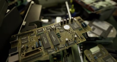 Motherboard on Workbench Surrounded By Other Electronic Components in Workshop