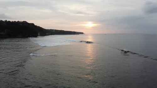 Aerial video of surfers at sunset in Bali. Aerial view of coastline and beach with big waves