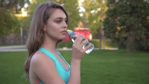 Woman Drinks Water After Workout in Park