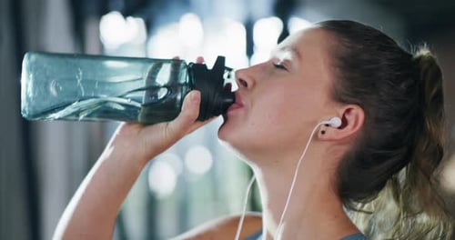 An attractive young sportswoman drinking water during a workout in a gym