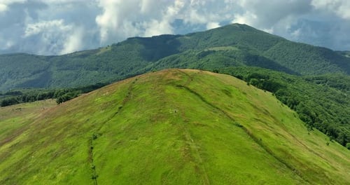 Flight over green mountain peaks. A beautiful sunny summer day at high altitude with thick clouds an