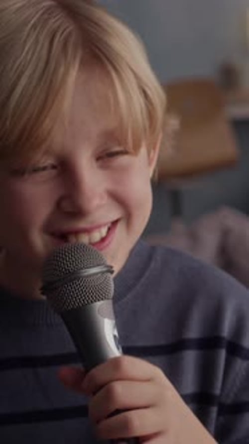 Smiling Blond Boy Sings Into Microphone