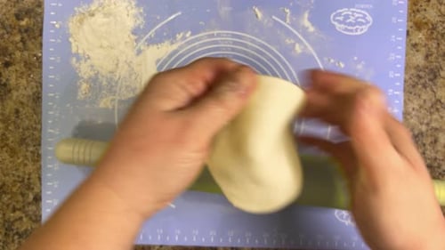 Hands Rolling Dough on Pastry Mat