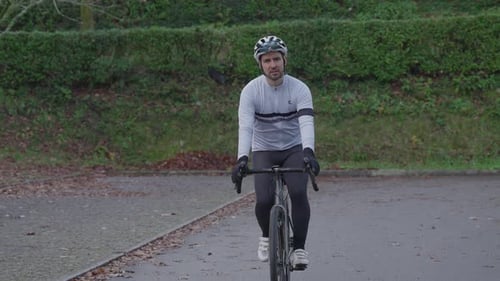 Cyclist riding bicycle toward camera on paved road