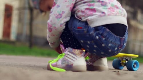 Kids with feet on yellow skateboard, blue wheels