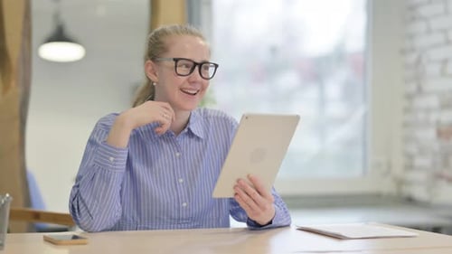 Woman at Table Uses Tablet to Video Chat