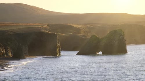 Küste mit Vulkanbergen und schwarzem Sandstrand bei Sonnenaufgang Meer Natur Sonniges Goldenes Wetter