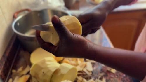 Hands of a Young African Woman Chopping a Yam to Cook It. Close-up View Inside the Kitchen