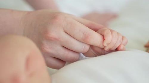 Mother Holding Newborn Infant's Hand in Close-Up