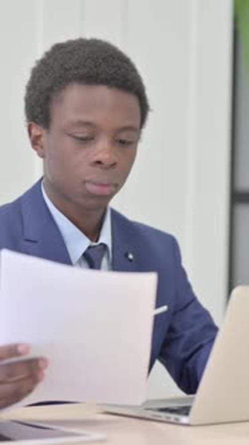 African Businessman Celebrating Success while Reading Documents in Office, Vertical Video