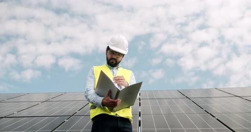 Techniker inspizieren Solarzellenfarm durch ein Feld mit Sonnenkollektoren