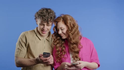 Young Couple Smiling and Using Smartphones