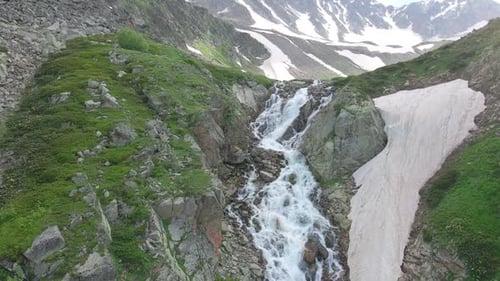 Luftbild der Landschaft mit Bergwasserfall gegen schneebedeckte kaukasische Pickel