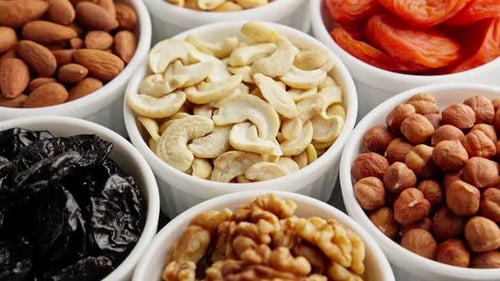 Different Nuts and Dried Fruits in White Bowls Rotating Natural Food