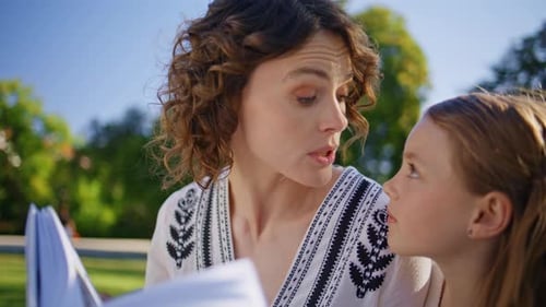Mom Kid Enjoying Novel Together at Summer Park Closeup Woman Daughter Talking