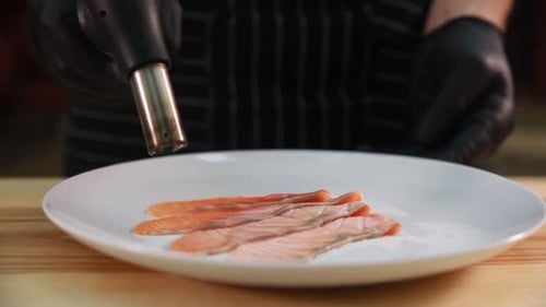 Chef Torching Raw Salmon Slices in Restaurant