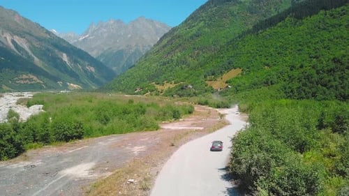 Car moves along dusty road among mountains in gorges.