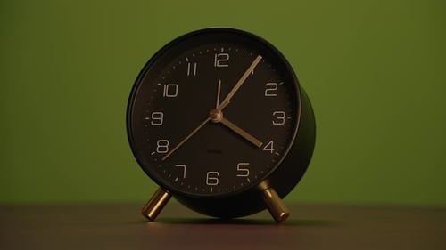 A Minimalist Black Alarm Clock Set Against a Striking Green Background Perfect for Any Setting