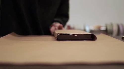 Craftsperson Wrapping Book in Brown Paper With Scissors