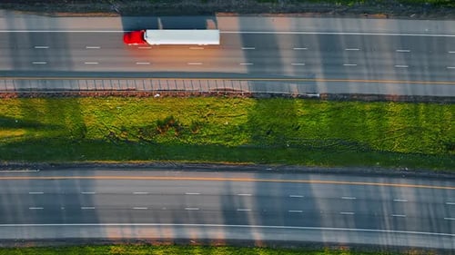 Lorries and cars drive by the highways to both sides. Top view on the roads at daytime.