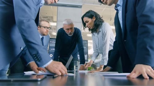 Professionals Collaborate on Documents and Laptop in Office