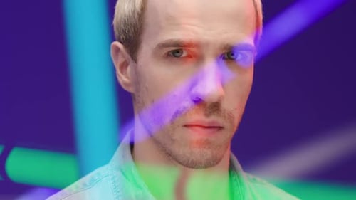 Confident man looks at camera in vibrant neon light fashion studio portrait