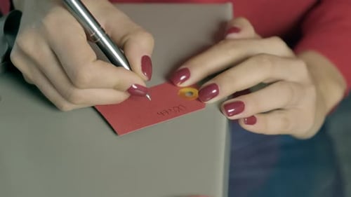 Hands write a message on a card