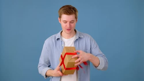 Man Shaking Wrapped Gift Box and Trying to Guess What Inside