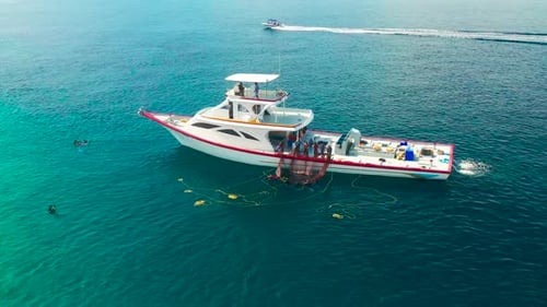 Fishermen on a white boat take out fishing nets with caught fish near a local island Ukulhas