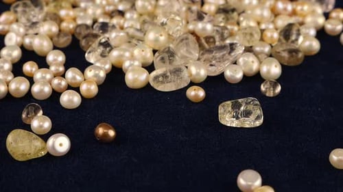 Natural pearls, quartz, rock crystal fall on dark blue velvet. Slow motion.