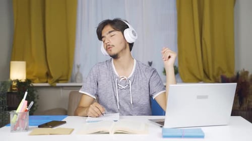 Young Adult Studying at Home Listening to Music