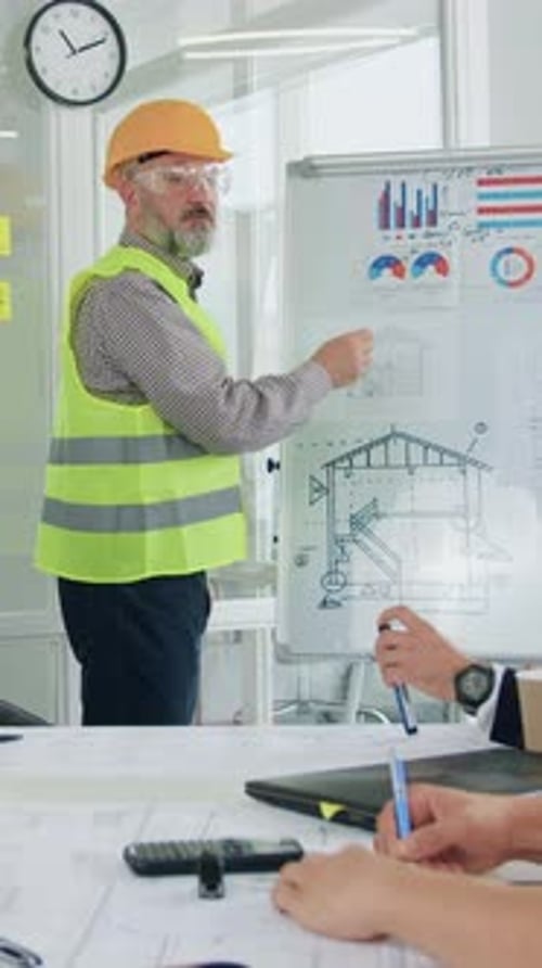 Attraktiver, zufriedener, hochqualifizierter bärtiger Architekt in Weste und Schutzhelm, der jedes seiner Mitglieder begrüßt