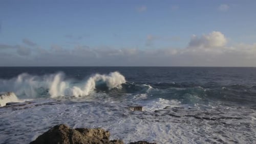Static Shot of Violent Waves Crashing into the Rocky Shoreline During the evening.