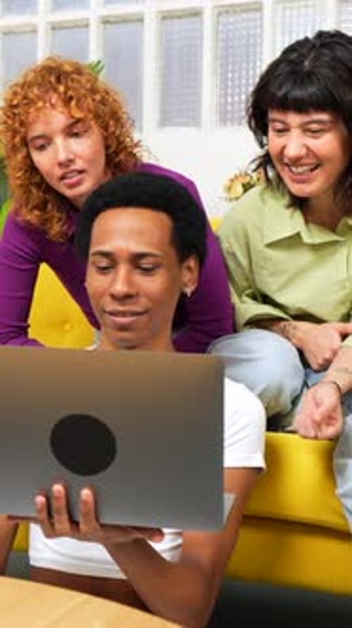 Personas LGBT usando una computadora portátil sentadas juntas en un sofá moderno