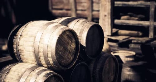 Wooden Barrels Arranged Near a Rustic Wooden Structure in a Warehouse