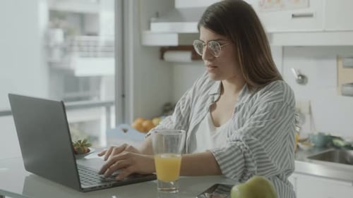Woman Working on Laptop in Bright Kitchen